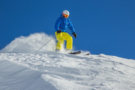 Skier skiing downhill in high mountains during sunny day.の写真素材