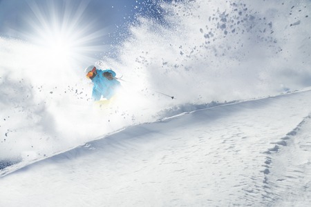 Skier skiing downhill in high mountains during sunny day.の写真素材