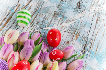 tulips and easter eggs on wooden background, close-up.