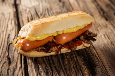 Hot dog with mustard and ketchupon wooden table.の写真素材