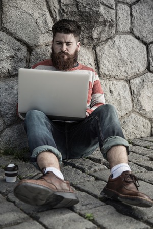 Handsome big moustache hipster man in the city with notebook.の写真素材