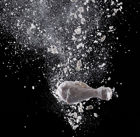 Fresh and raw chicken meat in motion on black background.の写真素材