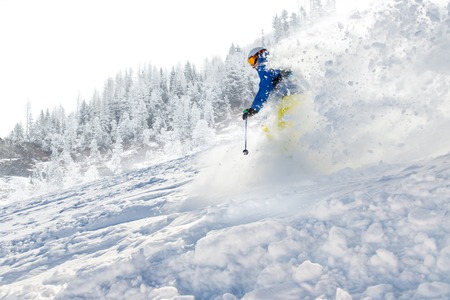 Skier skiing downhill during sunny day in high mountainsの写真素材