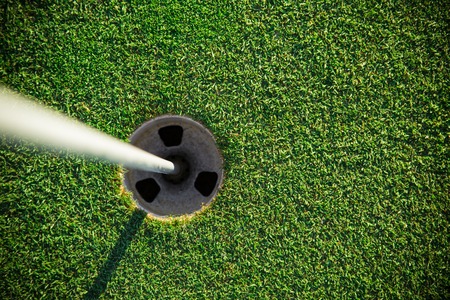 Close-up of golf hole with white flag rod.の写真素材