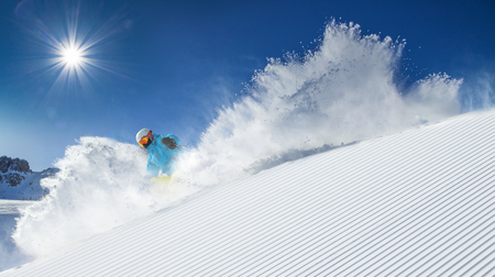 Skier skiing downhill during sunny day in high mountainsの写真素材