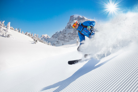 Skier skiing downhill during sunny day in high mountainsの写真素材