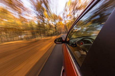 speeding car with motion blur background during autumn dayの写真素材