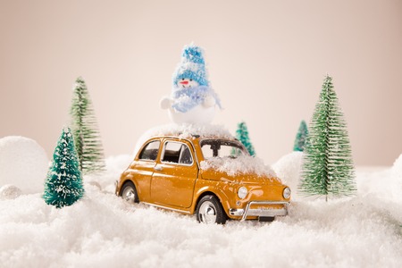 Miniature yellow car with spruce trees. Christmas theme.