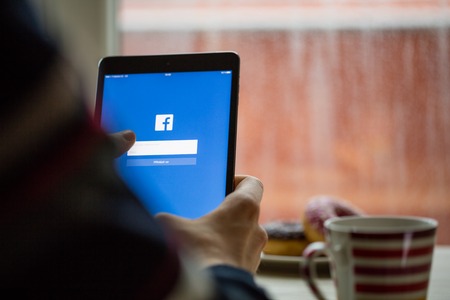 PRAGUE, CZECH REPUBLIC - NOVEMBER 17, 2015: A close-up photo of Apple iPad mini start screen with facebook login. Popular social media.のeditorial素材