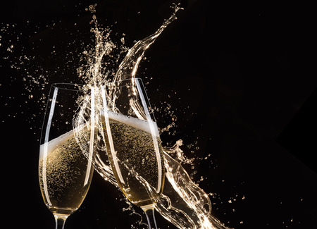 Glasses of champagne with splash, isolated on blackの写真素材