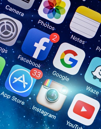 PRAGUE, CZECH REPUBLIC - NOVEMBER 17, 2015: A close-up photo of Apple iPhone 5s start screen with apps icons. Popular social media icons on smart phone screen.のeditorial素材