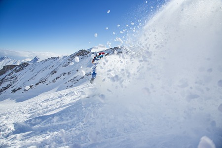 Skier skiing downhill during sunny day in high mountainsの写真素材