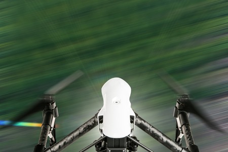 White drone quad copter with high resolution digital camera flying in the blue sky.