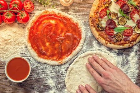 Pizza dough with ingredients on wooden background.の写真素材