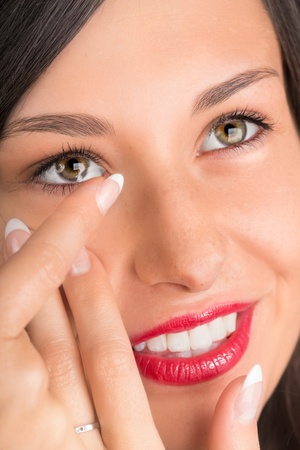 Young woman putting contact lens in her eye.の写真素材
