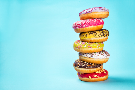 Donuts glazed with sprinkles on pastel blue background, close-up.の写真素材