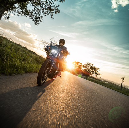 Man riding sportster motorcycle during sunset.の写真素材