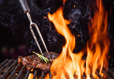Tasty Beef steaks on the grill with fire flamesの写真素材