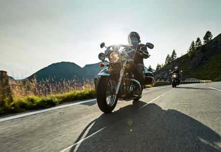 Motorcycle driver riding japanese high power cruiser in Alpine highway on famous Hochalpenstrasse, Austria, central Europe.