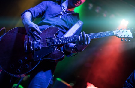 A man is playing guitar on stage, close-up.の写真素材