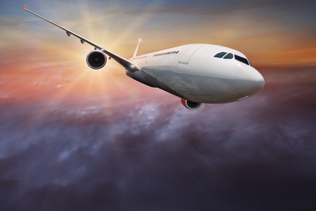 Commercial airplane flying above dramatic clouds.