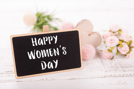 Small chalkboard for Women's day. Background with pink roses on old wooden table.の写真素材