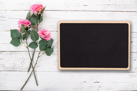 Flowers composition for Valentine's, Mother's or Women's Day. Pink rose with small blackboard on old white wooden background.の写真素材