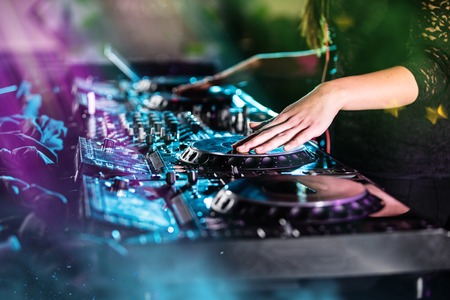 Dj mixes the track in the nightclub at a party