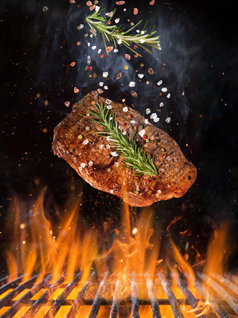 Tasty Beef steak flying on the grill with fire flamesの写真素材