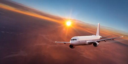 Commercial airplane flying above dramatic clouds during sunset.の写真素材
