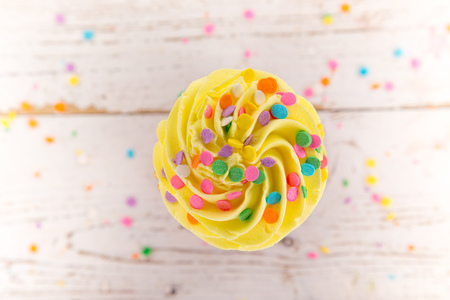 Colorful cup cake on wooden background.