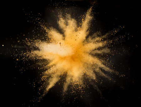 Golden powder explosion on black background.の写真素材