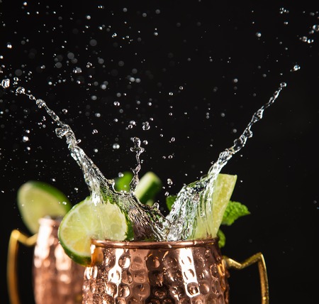 Famous splashing Moscow mule alcoholic cocktail in copper mugs.