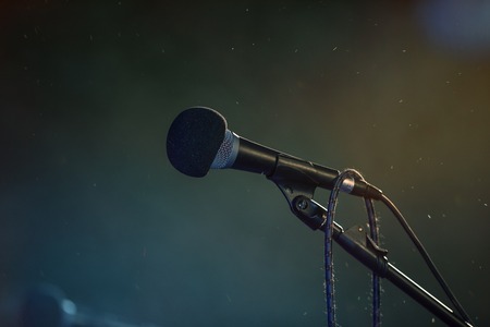 Metal microphone in holder on dark background