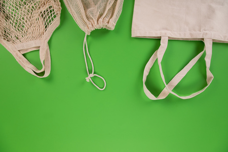Fresh vegetables in bio eco cotton bags on green background. Zero waste shopping concept.の写真素材