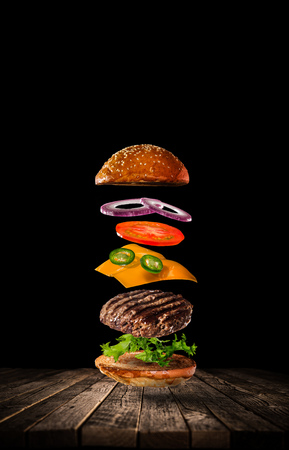Tasty hamburger with flying ingredients on darkの写真素材