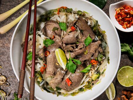 Pho bo asian food background with various ingredients on rustic stone background , top view.