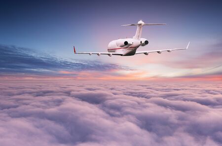 Private jet plane flying above dramatic clouds during sunset.