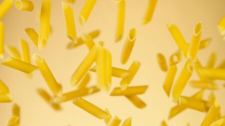Freeze motion of flying uncooked italian pasta on golden background.の写真素材