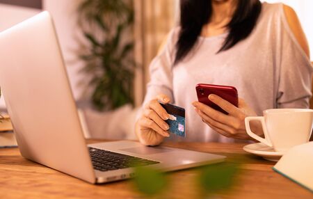 Woman is holding credit card and using laptop computer.