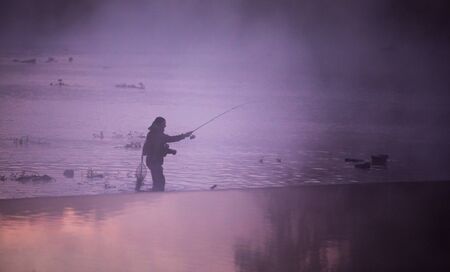 Men fishing in river with fly rod during summer morning.の写真素材