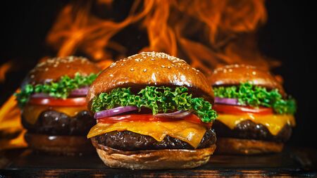 Tasty cheeseburgers, lying on vintage wooden cutting board.の写真素材