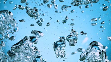Air bubbles in water against blue backgroundの写真素材