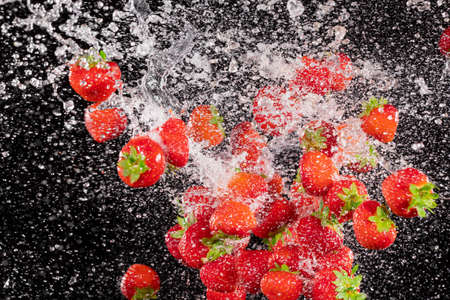 Fresh ripe strawberries flying on a black background.の写真素材