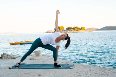 Gorgeous fit brunette woman in yoga pose on the beachの写真素材