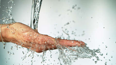 Close-up of female hands under the stream of splashing water