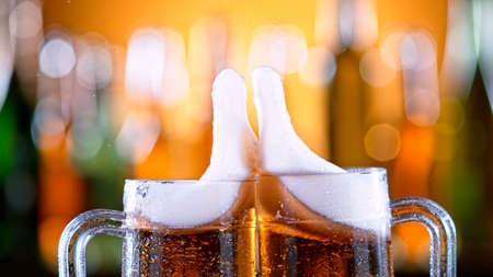 two glasses of beer toasting creating splash.の写真素材