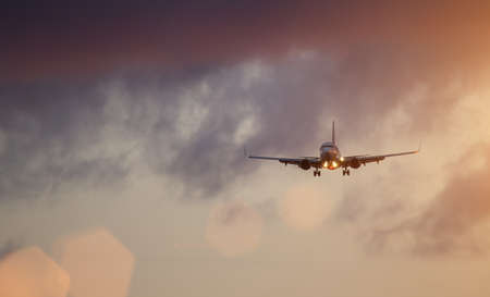 Commercial airplane jetliner flying above dramatic clouds.の写真素材