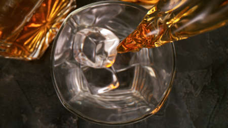top of view of pouring whiskey in the glass with ice cubesの写真素材