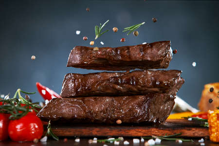 Delicious grilled beef steaks falling down on kitchen boardの写真素材